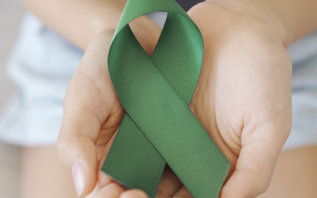 Two hands holding up a green ribbon, symbolizing Mental Health Awareness Month in May.